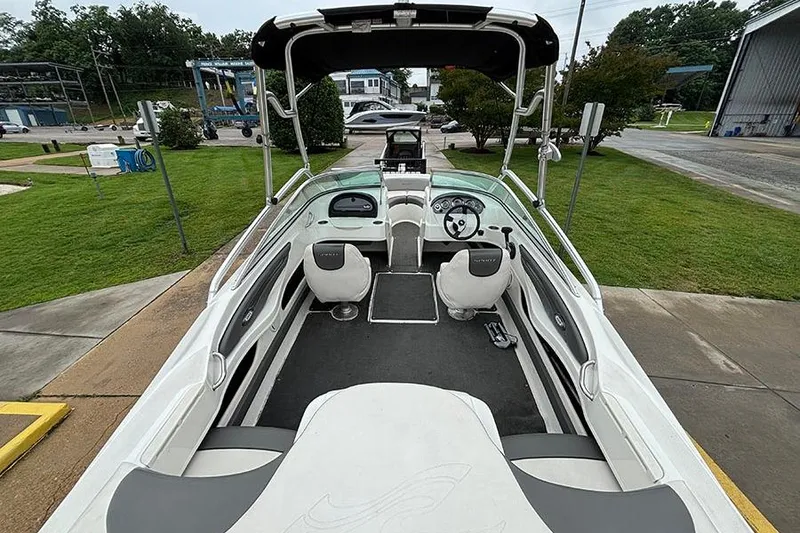 Slide: The Image of 2011 Sea Ray 205 Sport boat interior with seating and steering wheel, docked outdoors. - 8