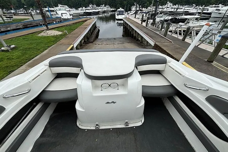Slide: The Image of 2011 Sea Ray 205 Sport boat interior at marina, featuring seating and cup holders. - 9