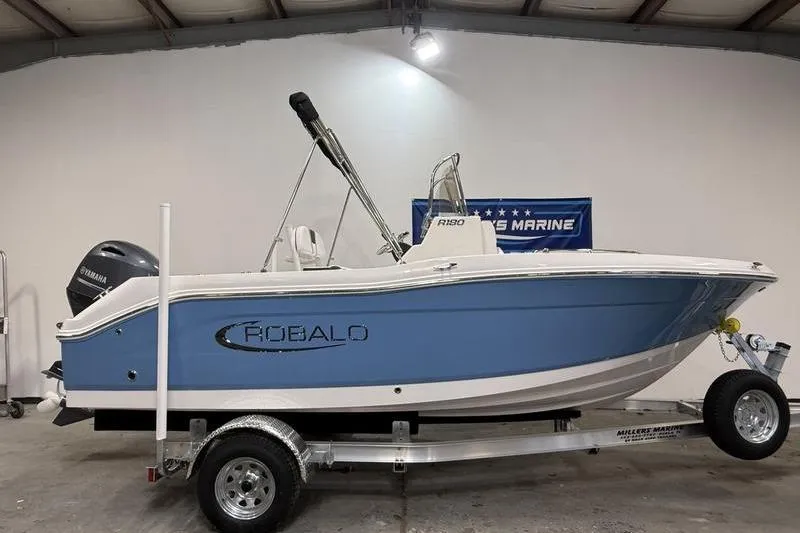 The Image of 2026 Robalo R180 Center Console boat on trailer in warehouse. - 0