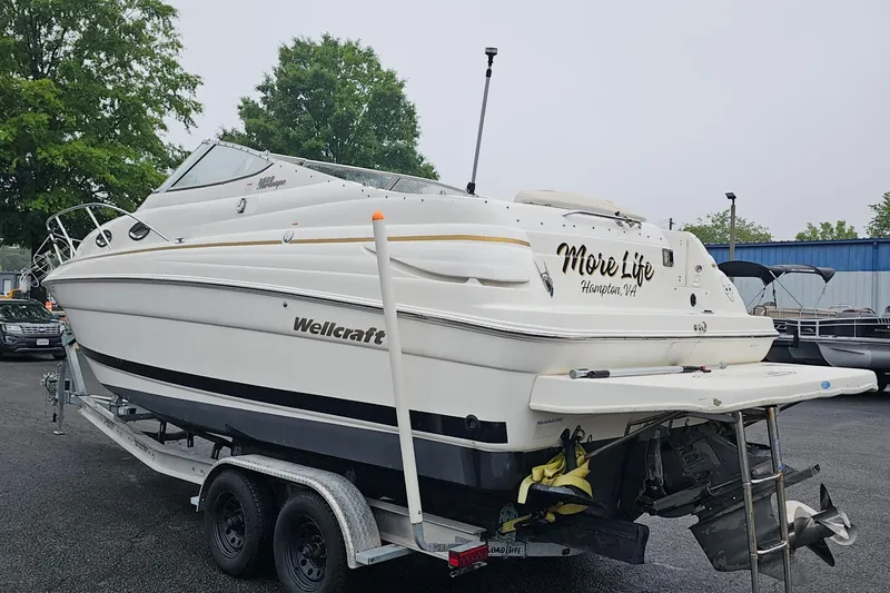 Slide: The Image of 2002 Wellcraft 2600 Martinique boat on trailer, labeled "More Life," parked outdoors. - 2