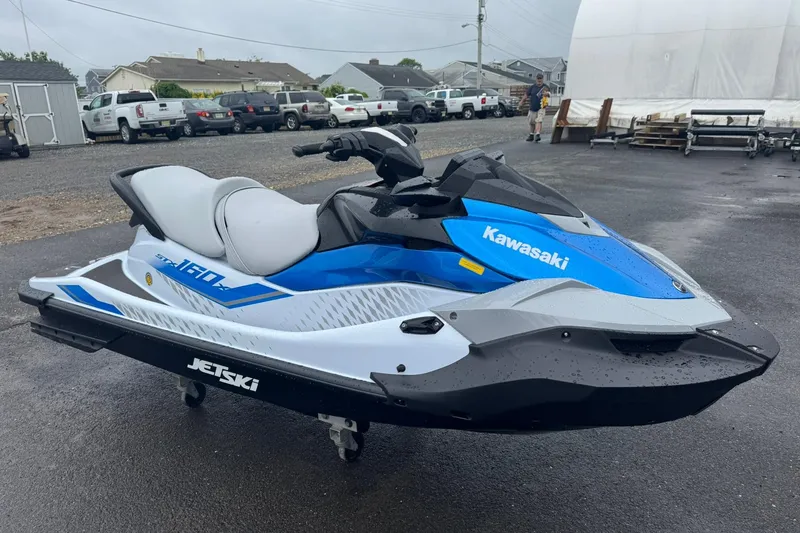 Slide: The Image of 2026 Kawasaki STX160 Jet Ski in blue and white, parked outdoors on a wet surface. - 2