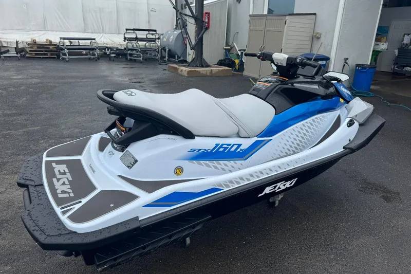 Slide: The Image of 2026 Kawasaki STX160X jet ski parked on wet pavement. - 5