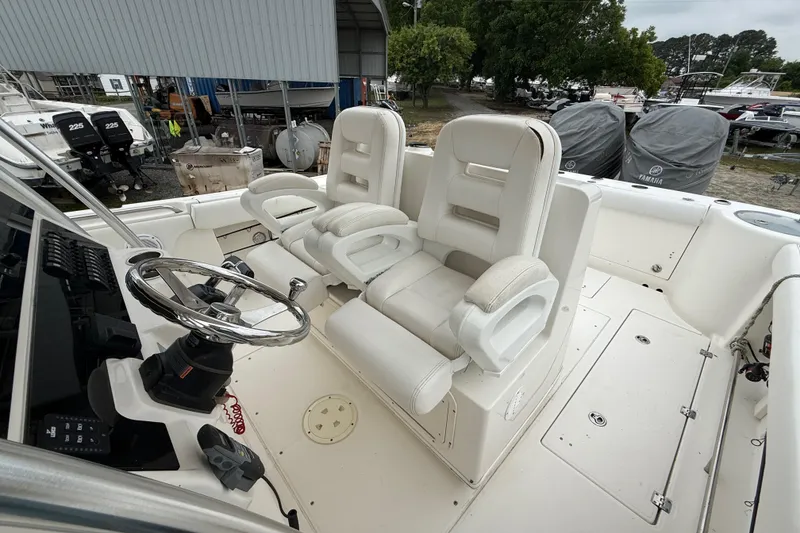 Slide: The Image of 2008 Robalo R300 Center Console boat interior with dual white captain's chairs and steering wheel. - 15