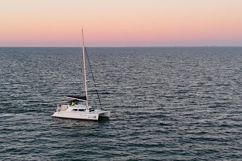 Slide: The Image of 2009 Lagoon 440 catamaran sailing at sunset on the ocean. - 2