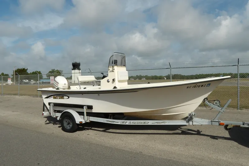 Slide: The Image of 2005 May-Craft 1800 Skiff boat on trailer, parked near a fenced area. - 2