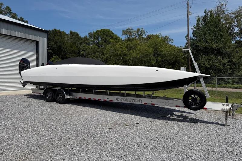 Slide: The Image of 2024 Fountain 34 Thundercat boat on trailer, parked outdoors near a garage. - 48