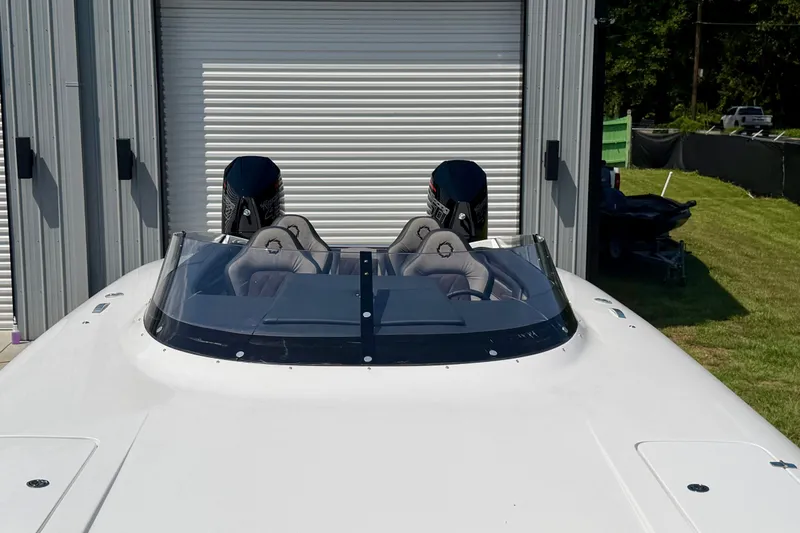 Slide: The Image of 2024 Fountain 34 Thundercat boat with dual engines, parked near a metal building. - 29
