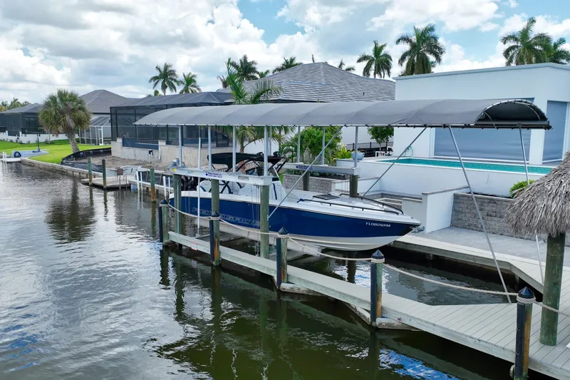 Slide: The Image of 2018 Renegade 32' Cuddy boat docked under canopy, surrounded by waterfront homes and palm trees. - 4