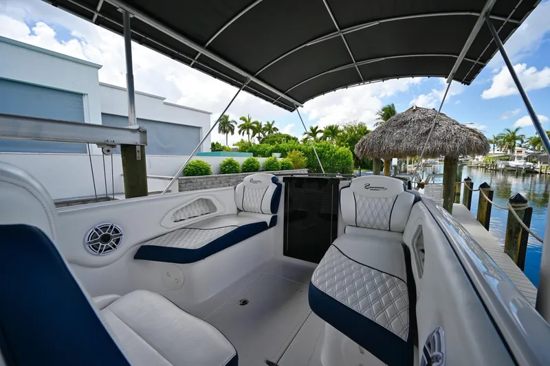 Slide: The Image of 2018 Renegade 32' Cuddy boat interior with cushioned seating and canopy, docked by a waterfront. - 8