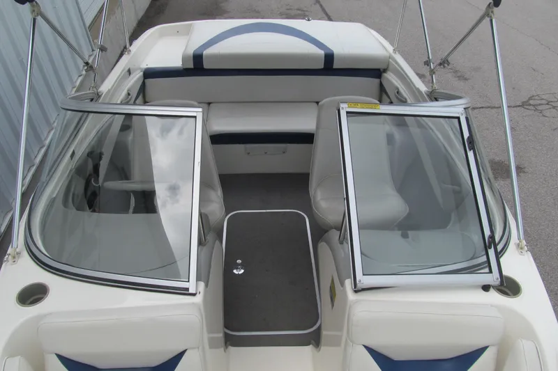 Slide: The Image of 2005 Bayliner 185 boat interior with seating and windshield, docked on pavement. - 10