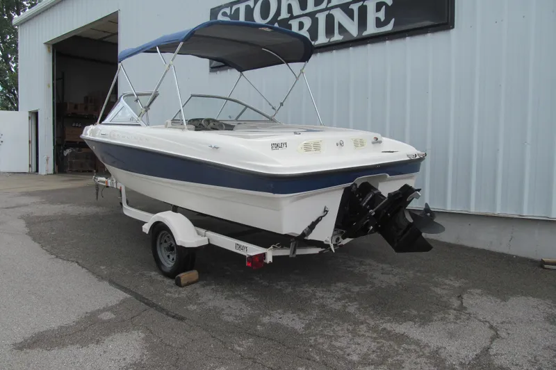 Slide: The Image of 2005 Bayliner 185 boat with canopy on trailer, parked outside marine store. - 3
