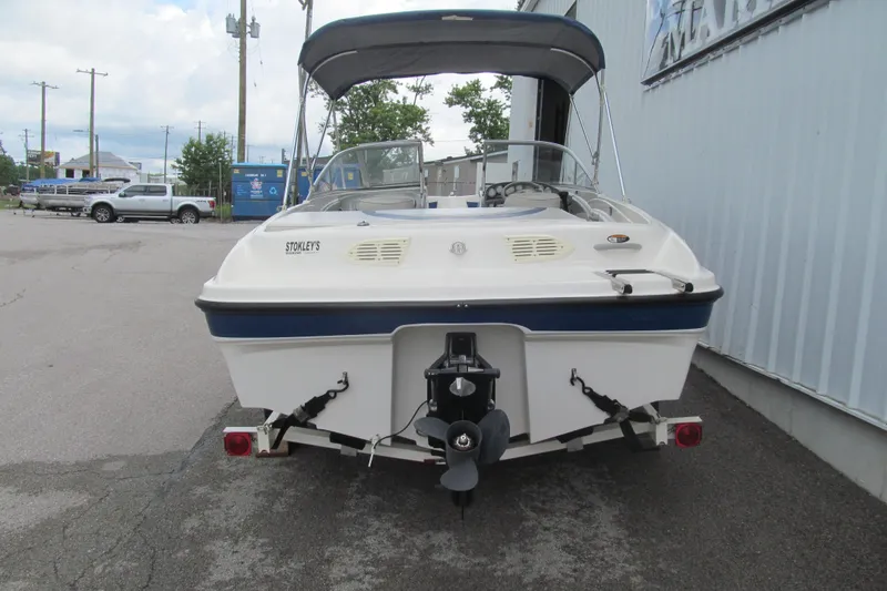 Slide: The Image of 2005 Bayliner 185 boat with canopy, parked on a trailer in an industrial area. - 4