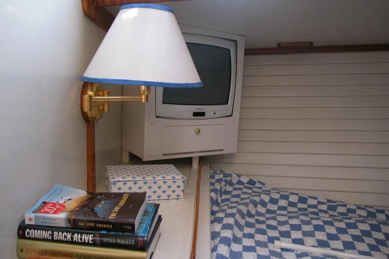 Slide: The Image of Cozy cabin interior of 1970 Hinckley Bermuda 40 with books, TV, and checkered bedding. - 35