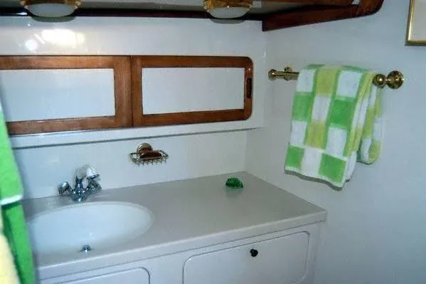 Slide: The Image of 1970 Hinckley Bermuda 40 yacht bathroom with sink, wooden accents, and green checkered towel. - 36