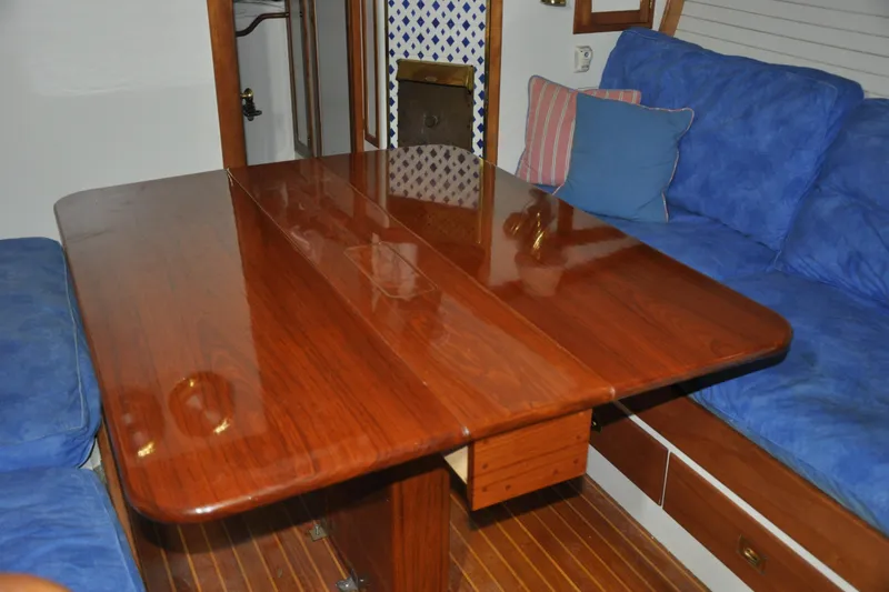Slide: The Image of Interior of 1970 Hinckley Bermuda 40 yacht with polished wooden table and blue cushions. - 38