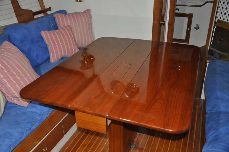 Slide: The Image of Interior of a 1970 Hinckley Bermuda 40 yacht with polished wooden table and blue seating. - 39