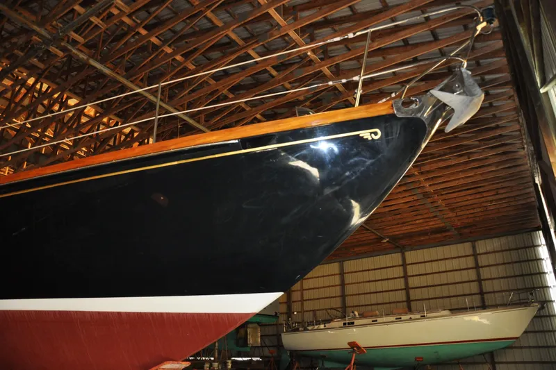Slide: The Image of 1970 Hinckley Bermuda 40 sailboat in a wooden boathouse, showcasing its sleek hull design. - 9