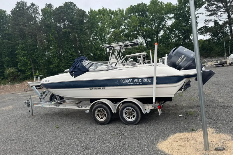 The Image of 2013 Stingray 204 LR boat on trailer, labeled "Toad's Wild Ride," parked outdoors. - 1