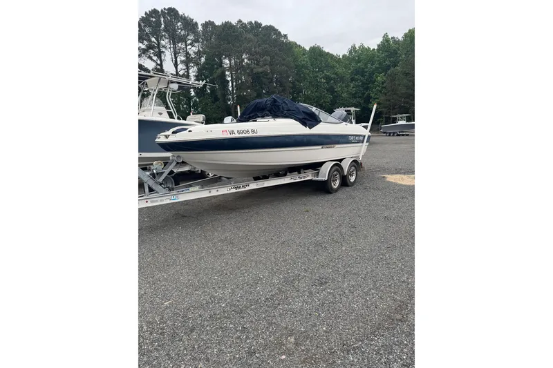 Slide: The Image of 2013 Stingray 204 LR boat on trailer in parking lot, surrounded by trees. - 11
