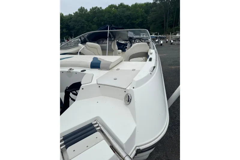 Slide: The Image of 2013 Stingray 204 LR boat with white seating, docked near a forested area. - 3