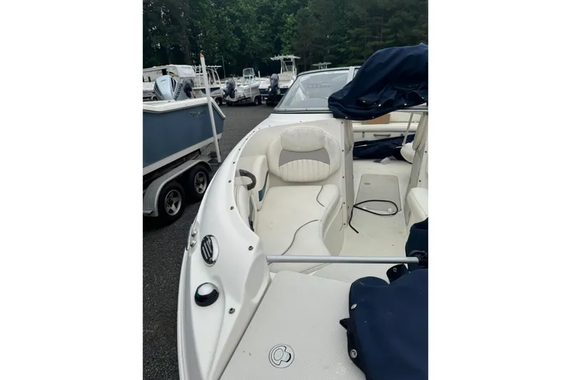 Slide: The Image of 2013 Stingray 204 LR boat interior with seating, parked outdoors. - 9