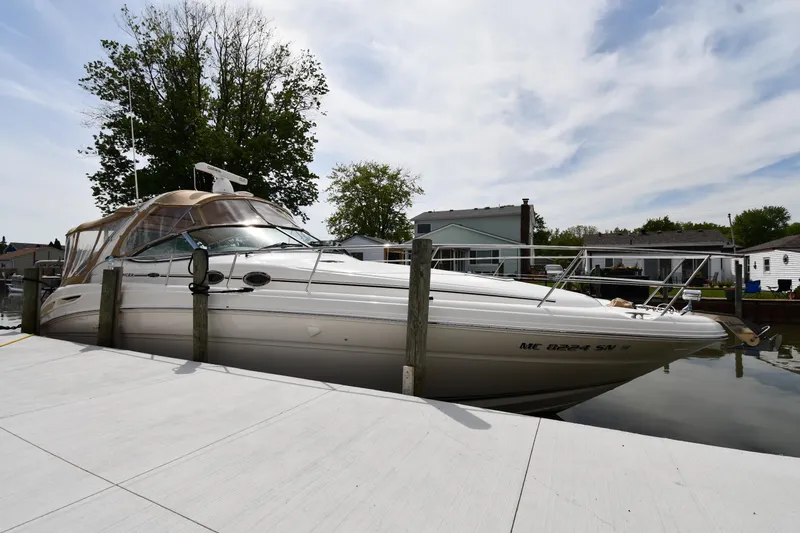 The Image of 2003 Sea Ray 360 Sundancer yacht docked at a marina, surrounded by trees and houses. - 1