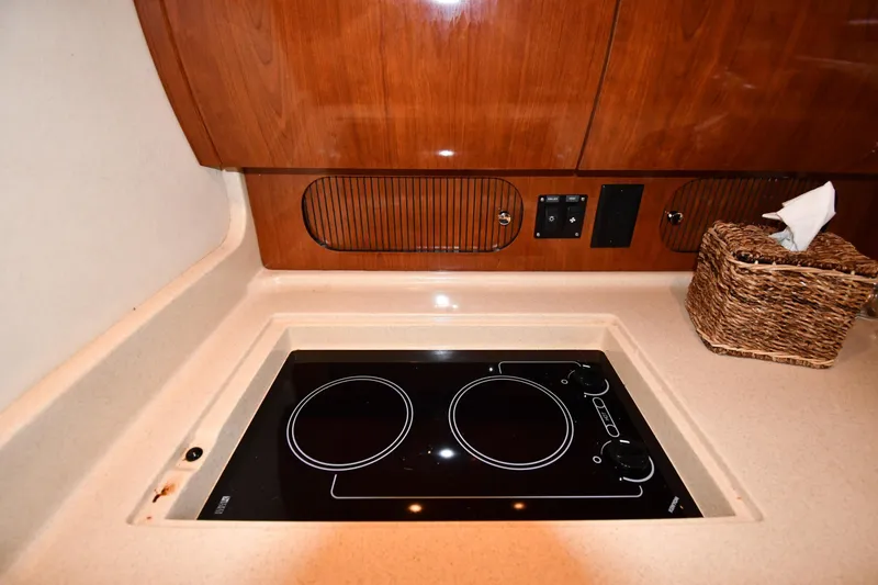 Slide: The Image of 2003 Sea Ray 360 Sundancer galley with electric stovetop and wooden cabinetry. - 40
