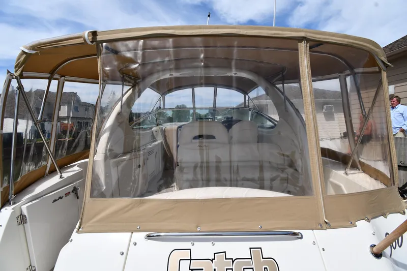 Slide: The Image of 2003 Sea Ray 360 Sundancer boat with tan canopy and clear enclosure, docked near houses. - 8