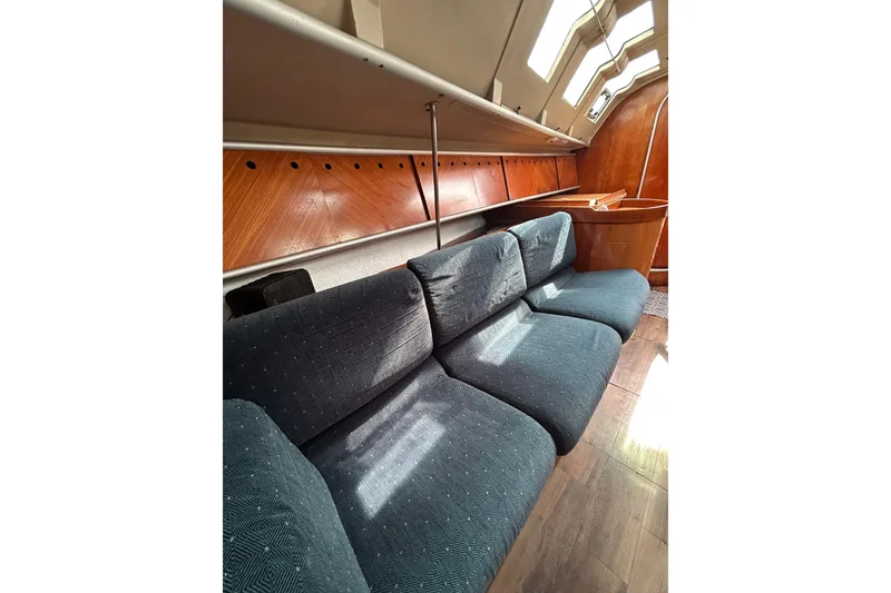 Slide: The Image of Interior of 1992 Beneteau First 35s5 sailboat with blue cushioned seating and wooden accents. - 11
