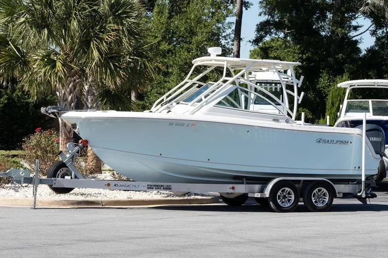 The Image of 2023 Sailfish 245 DC boat on trailer, parked outdoors with trees in background. - 1