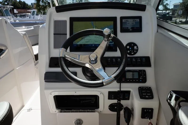 Slide: The Image of 2023 Sailfish 245 DC boat dashboard with steering wheel and navigation display. - 18