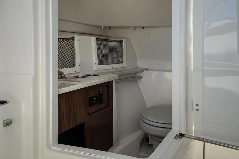 Slide: The Image of 2023 Sailfish 245 DC boat interior with compact bathroom and storage compartments. - 23