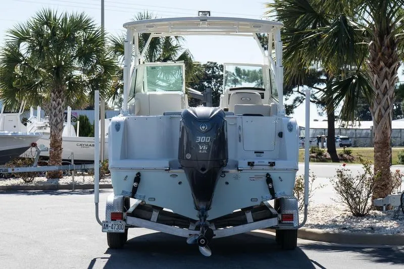 Slide: The Image of 2023 Sailfish 245 DC boat with 300 V6 engine on trailer, surrounded by palm trees. - 5