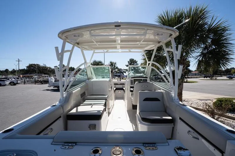 Slide: The Image of 2023 Sailfish 245 DC boat interior with seating and canopy, parked near palm trees. - 9