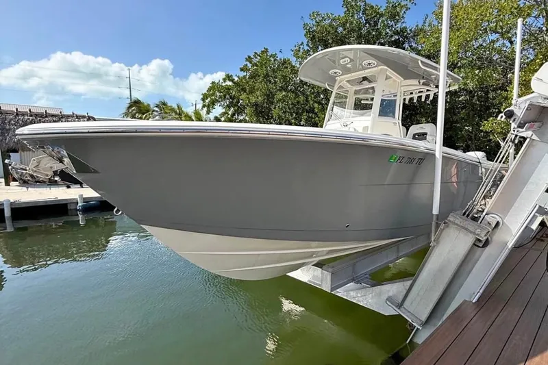 The Image of 2024 Cobia 280 Center Console boat docked on a lift, sunny day. - 1