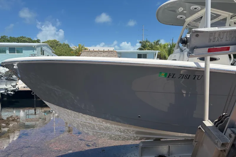 Slide: The Image of 2024 Cobia 280 Center Console boat on lift, sunny day, waterfront setting. - 3