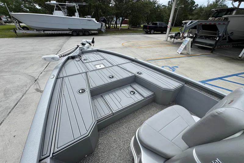 Slide: The Image of 2021 Avid 21 FS boat interior with gray seating and deck, parked outdoors. - 18
