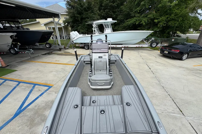 Slide: The Image of 2021 Avid 21 FS boat in parking lot, surrounded by other boats and vehicles. - 21
