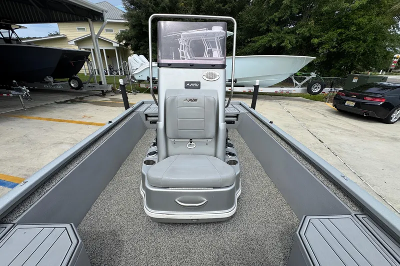 Slide: The Image of 2021 Avid 21 FS boat interior with gray seating and console, parked outdoors. - 22