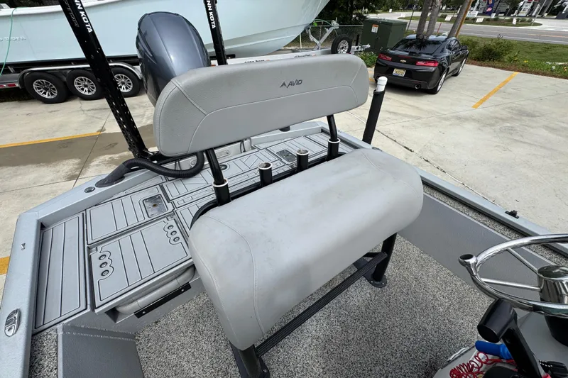 Slide: The Image of 2021 Avid 21 FS boat interior with seating and steering wheel, parked outdoors. - 27