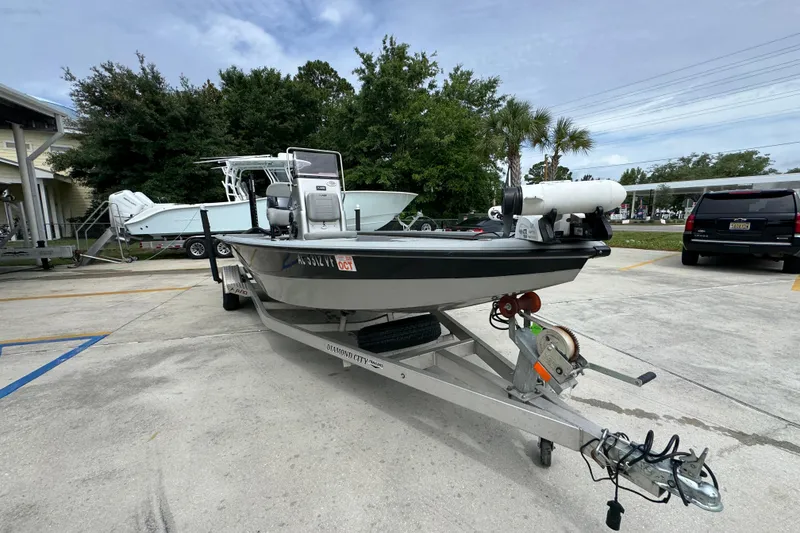 Slide: The Image of 2021 Avid 21 FS boat on trailer in parking lot, surrounded by trees and vehicles. - 6