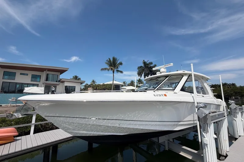 The Image of 2022 Boston Whaler 380 Realm boat docked near modern waterfront home. - 0