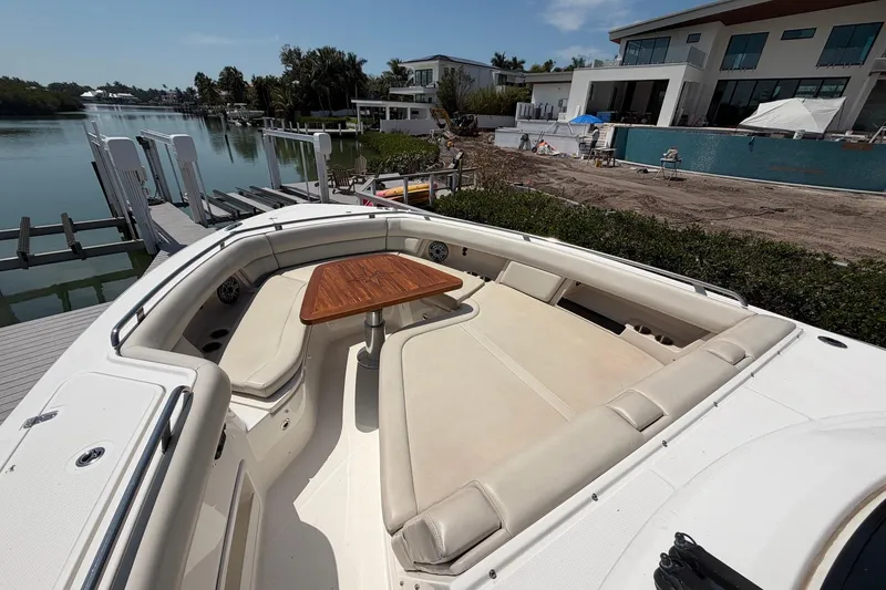 Slide: The Image of 2022 Boston Whaler 380 Realm boat with spacious seating and wooden table docked by waterfront homes. - 8
