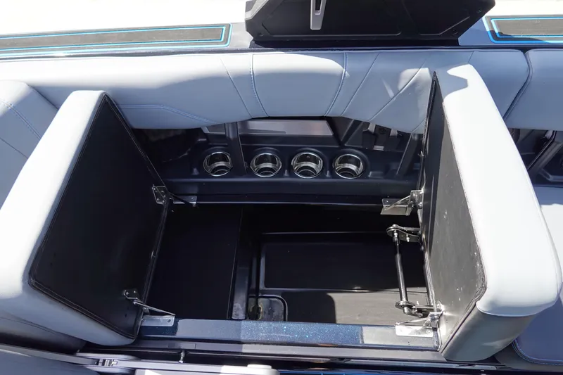 Slide: The Image of 2024 Malibu Wakesetter 23 MXZ interior storage compartment with open seats and cup holders. - 24