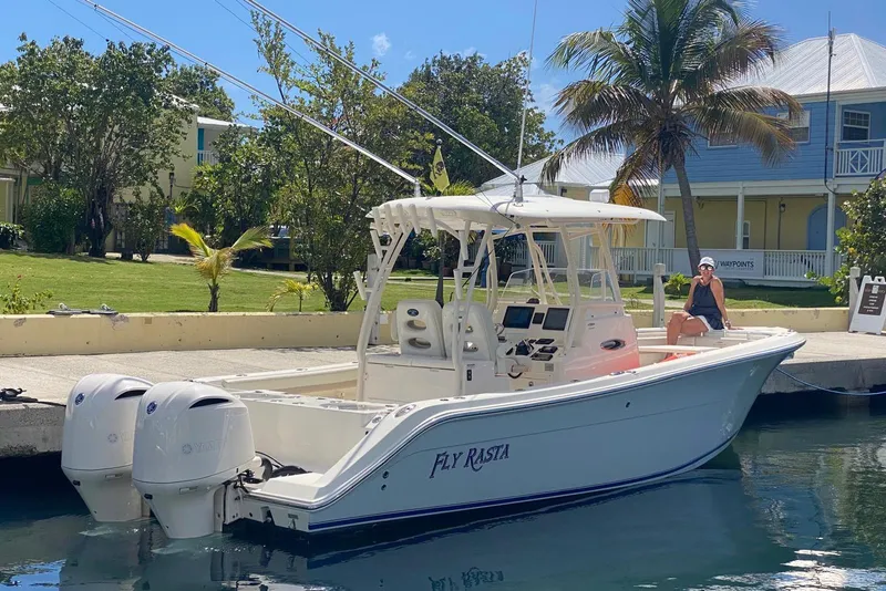 Slide: The Image of 2017 Cobia 296 Center Console boat docked with palm trees and a person onboard. - 2