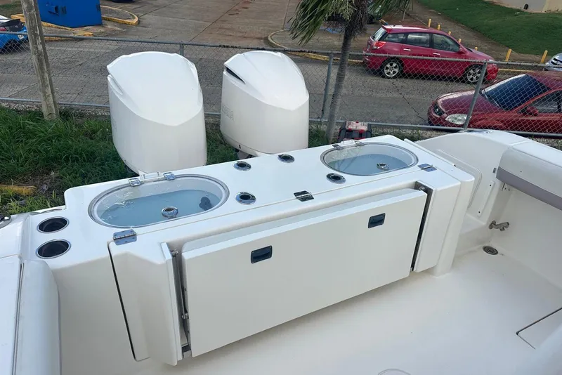 Slide: The Image of 2017 Cobia 296 Center Console boat with dual outboard engines and livewell compartments. - 34