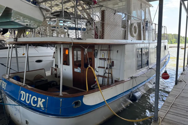 Slide: The Image of 1984 Kadey-Krogen 36 Manatee boat docked, featuring a wooden deck and nautical equipment. - 3