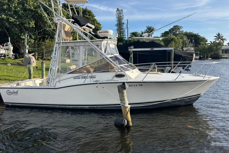 Slide: The Image of 2003 Carolina Classic 28 boat docked by the water, featuring fishing equipment. - 2