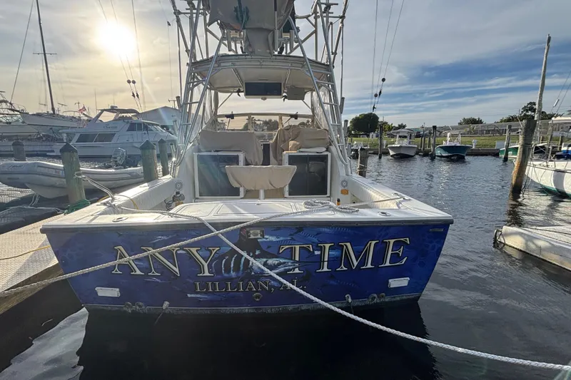 Slide: The Image of 2003 Carolina Classic 28 boat docked at marina, rear view with "ANY TIME" name. - 5