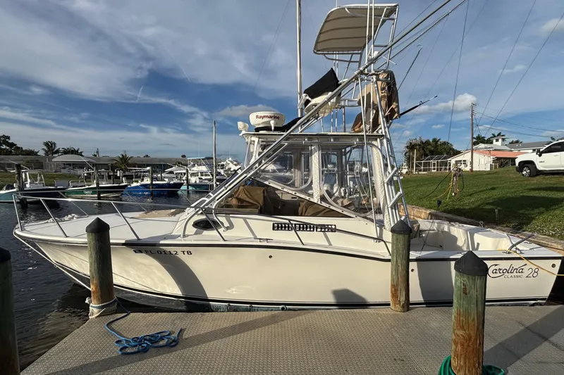 Slide: The Image of 2003 Carolina Classic 28 boat docked at marina under clear blue sky. - 8
